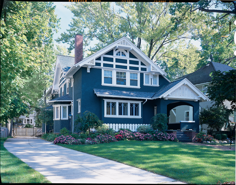 Imagen de fachada de casa azul clásica de tamaño medio de dos plantas con revestimiento de estuco, tejado a dos aguas y tejado de teja de madera