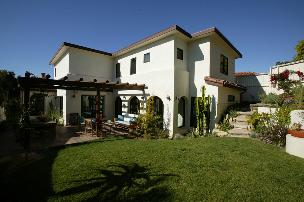 Example of a mid-sized tuscan white three-story stucco flat roof design in Orange County