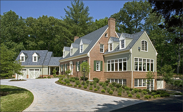 Cette image montre une grande façade de maison verte traditionnelle en brique à deux étages et plus avec un toit à deux pans.