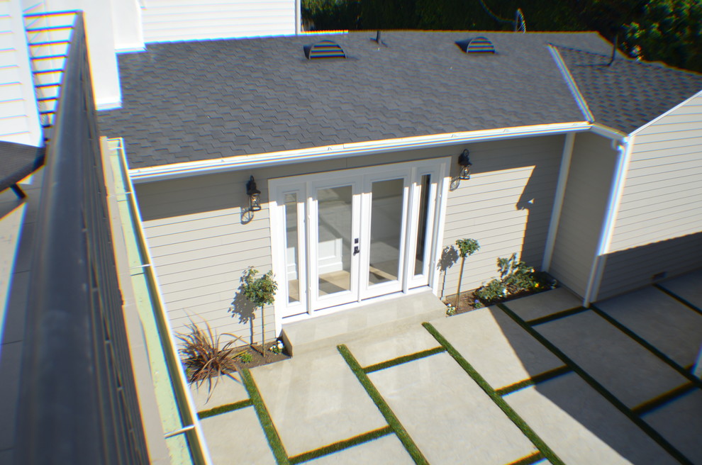 На фото: серый, маленький, двухэтажный частный загородный дом в классическом стиле с облицовкой из ЦСП, двускатной крышей и крышей из гибкой черепицы для на участке и в саду с