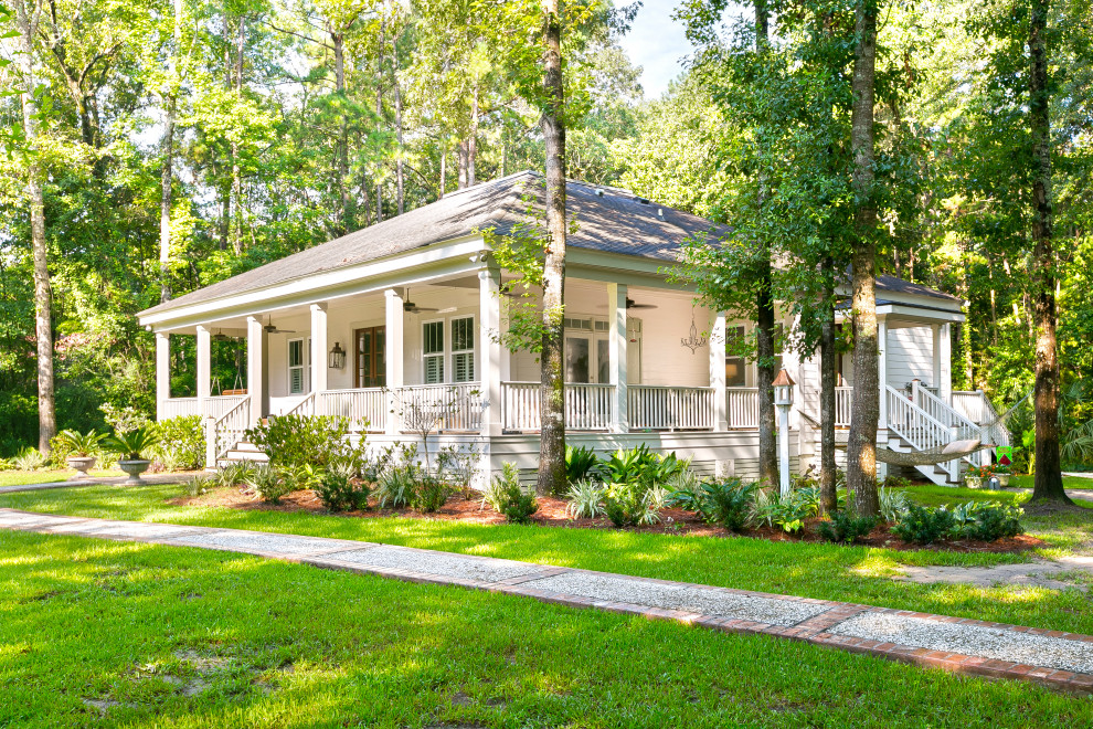 Einstöckiges Landhaus Einfamilienhaus mit Faserzement-Fassade, Schindeldach, weißer Fassadenfarbe, Walmdach und grauem Dach in Charleston