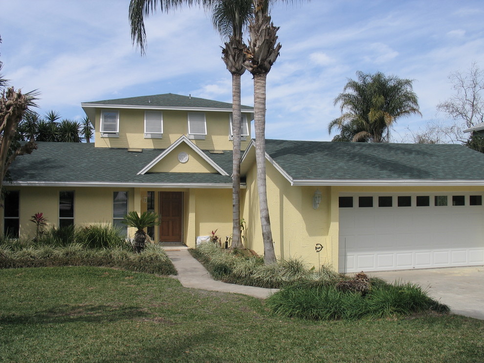 Foto på ett mellanstort tropiskt gult hus, med tre eller fler plan och stuckatur