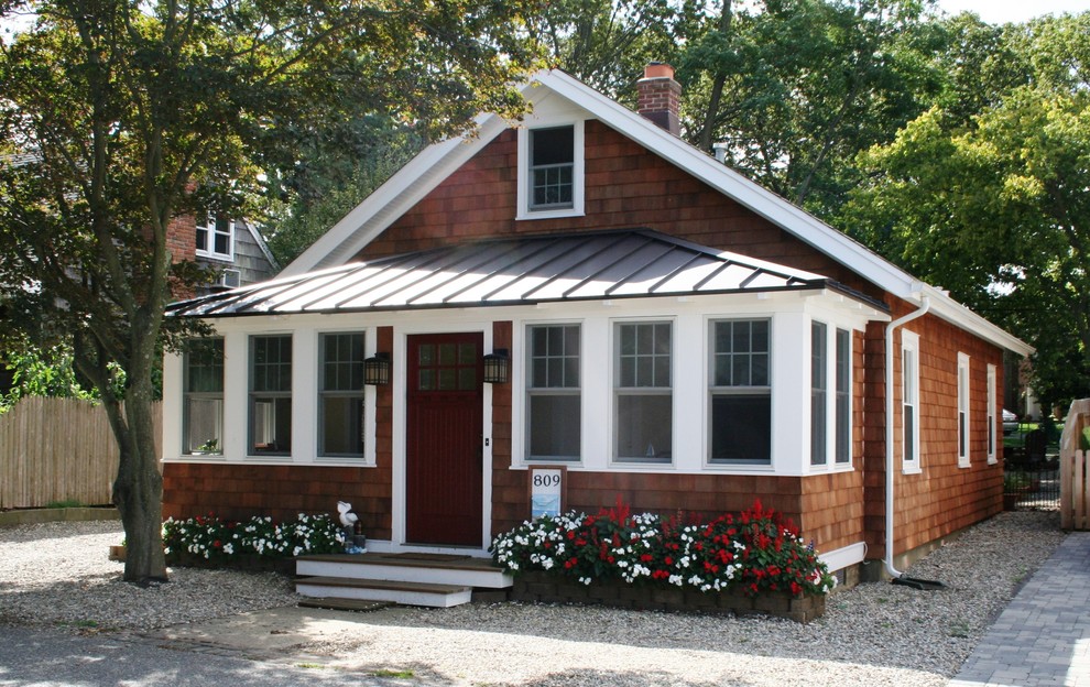 Imagen de fachada de casa marrón marinera pequeña de una planta con revestimiento de madera, tejado a cuatro aguas y tejado de metal