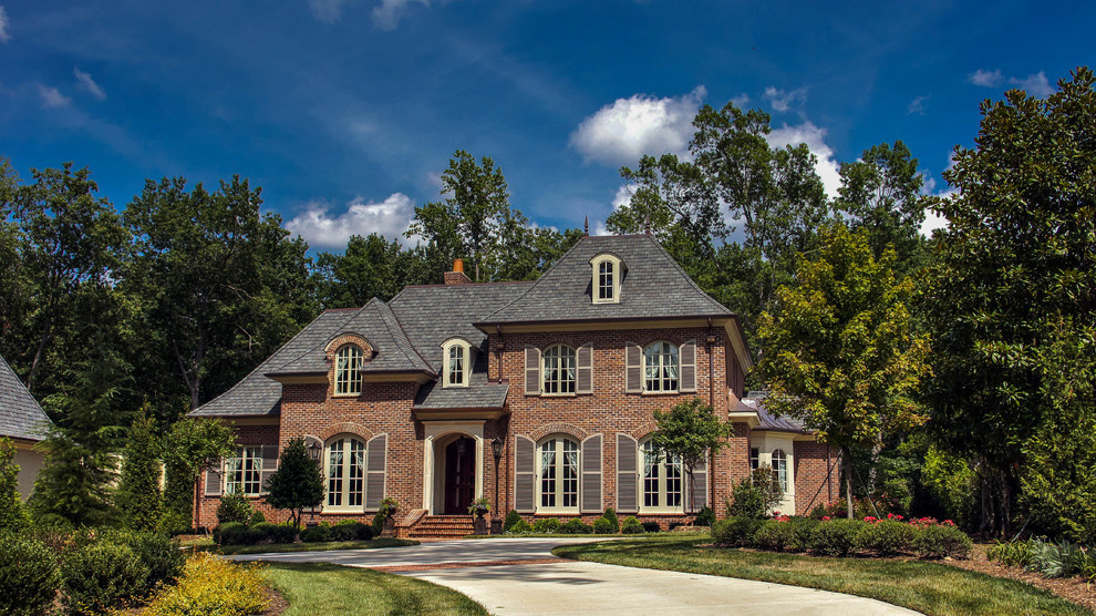 Exemple d'une grande façade de maison rouge tendance en brique à deux étages et plus avec un toit à croupette.