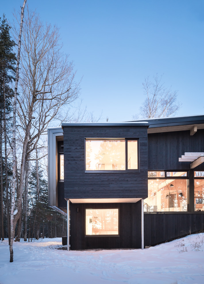 Réalisation d'une petite façade de maison noire chalet en bois à niveaux décalés.