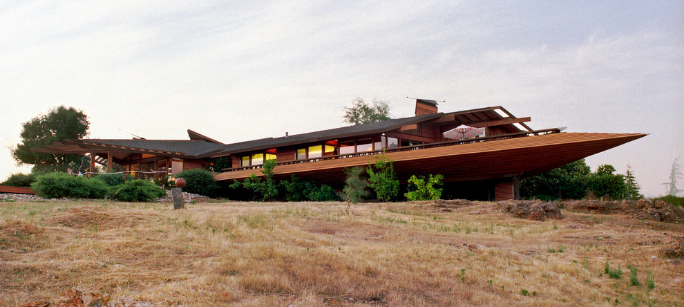 Diseño de fachada marrón moderna grande de dos plantas con revestimiento de madera y tejado a cuatro aguas