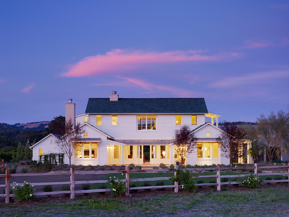 Immagine della facciata di una casa bianca country a due piani con rivestimento in legno