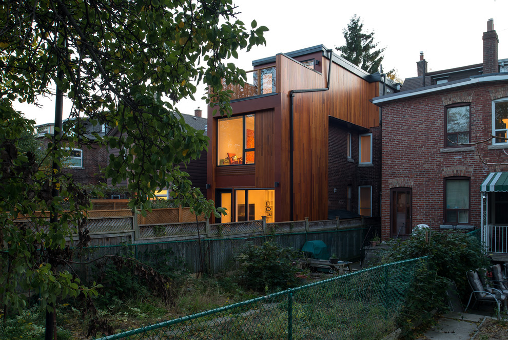 Foto de fachada de casa actual de tres plantas con revestimiento de madera