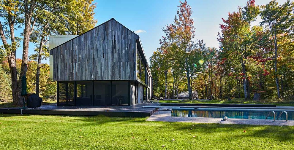 На фото: двухэтажный, деревянный, серый частный загородный дом среднего размера в современном стиле с полувальмовой крышей и металлической крышей с