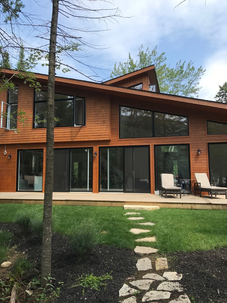 Стильный дизайн: большой, двухэтажный, деревянный, коричневый частный загородный дом в современном стиле с двускатной крышей и крышей из гибкой черепицы - последний тренд