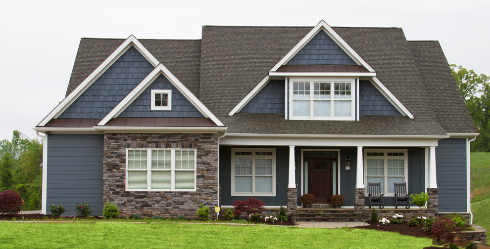 Cette image montre une façade de maison bleue traditionnelle de taille moyenne et à un étage avec un revêtement en vinyle et un toit mixte.