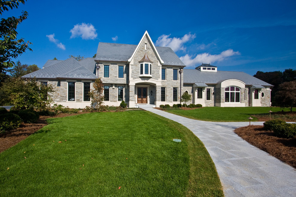 Large traditional gray two-story stone exterior home idea in Other