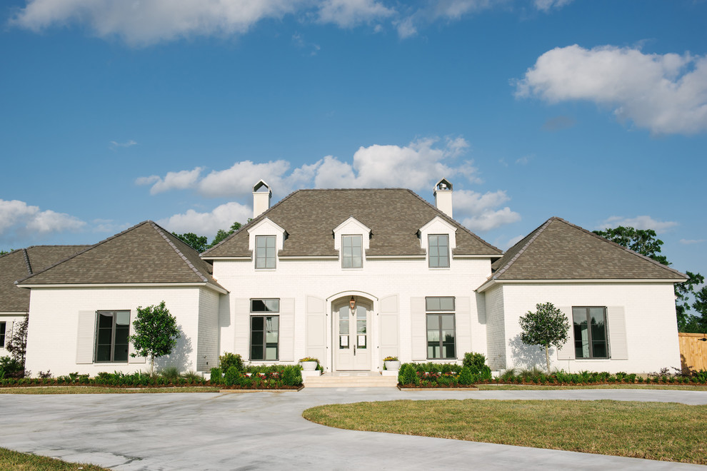 Large elegant white one-story brick house exterior photo in New Orleans with a hip roof and a shingle roof