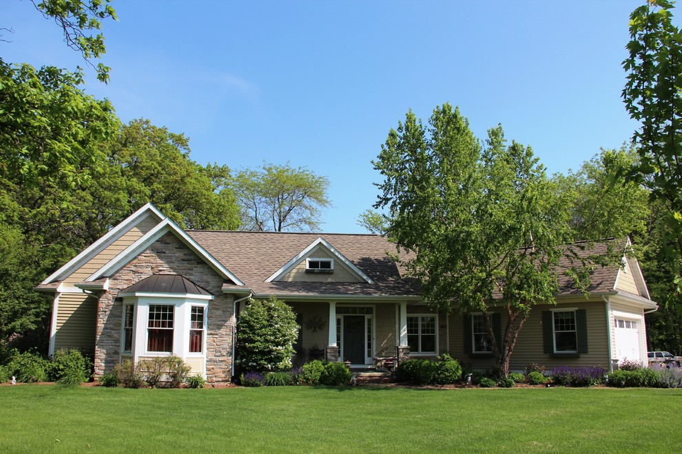 Imagen de fachada de casa beige de estilo americano de una planta con revestimiento de madera, tejado a dos aguas y tejado de teja de madera