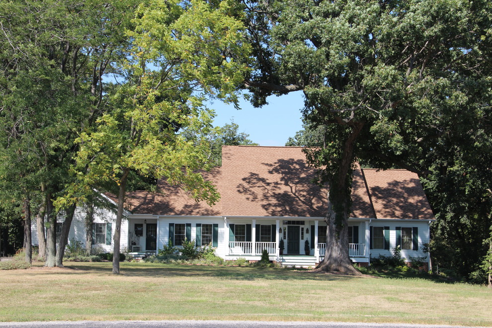 Einstöckiges Landhausstil Einfamilienhaus mit Betonfassade, weißer Fassadenfarbe, Satteldach und Schindeldach in Sonstige