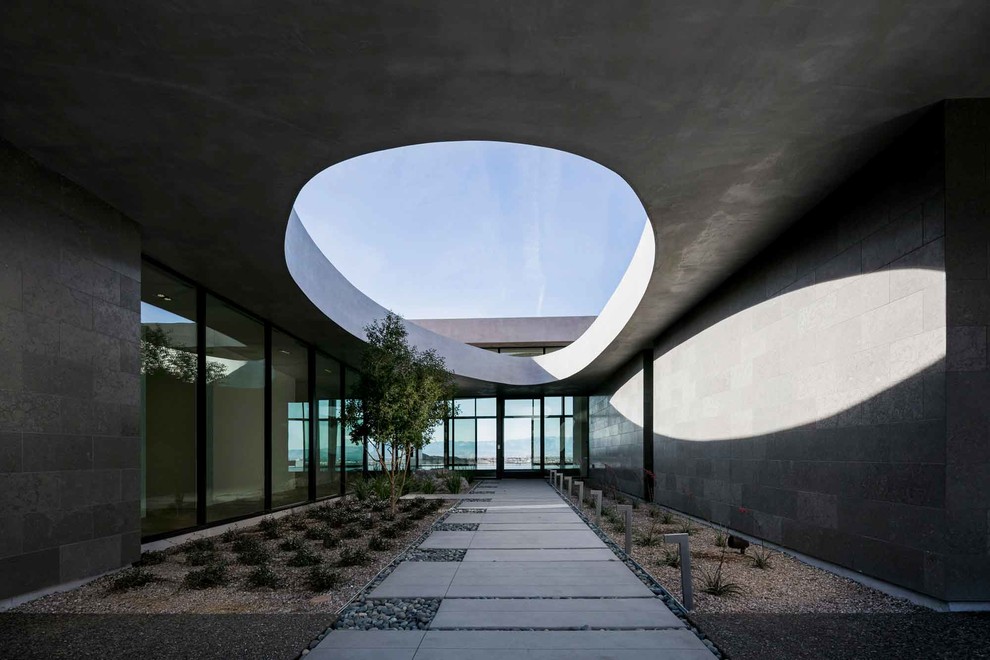 На фото: огромный, одноэтажный, серый частный загородный дом в стиле модернизм с облицовкой из бетона