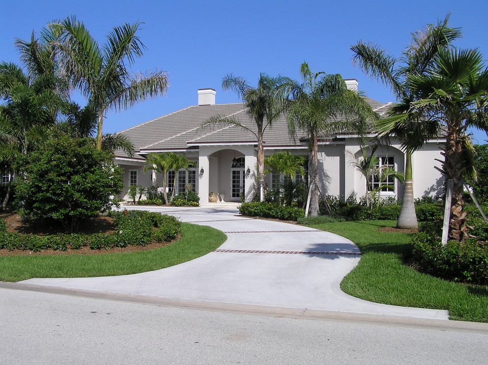 Large island style one-story stucco exterior home photo in Miami with a hip roof