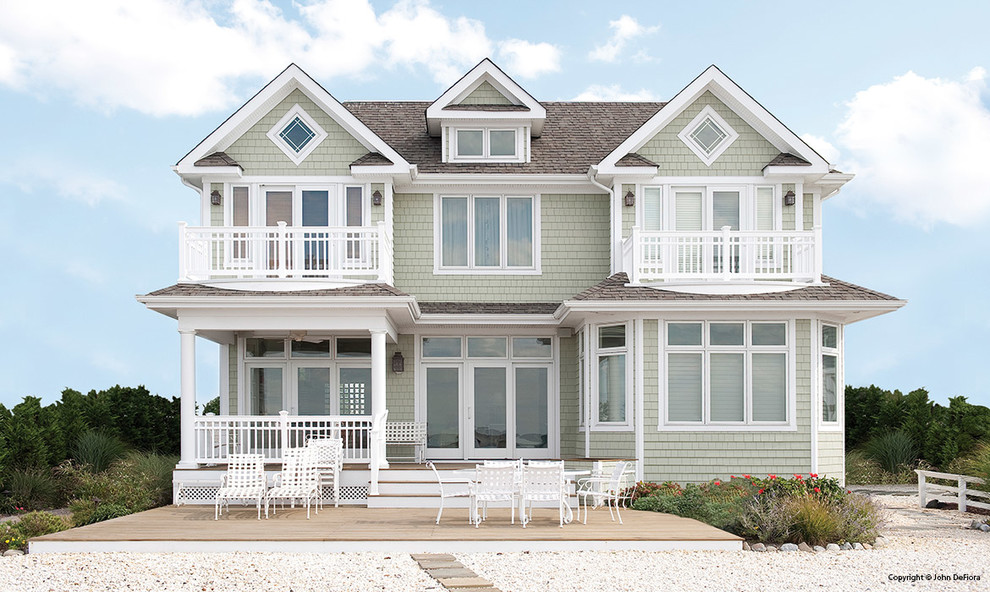 Exemple d'une très grande façade de maison verte bord de mer en bois à deux étages et plus.