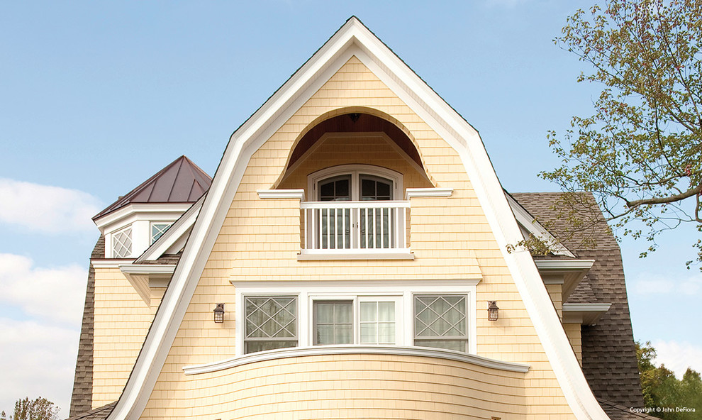 Cette photo montre une grande façade de maison jaune romantique en bois à deux étages et plus.