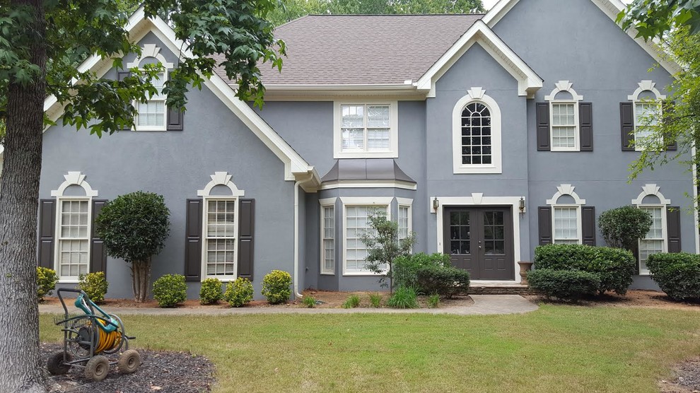 Large elegant gray two-story stucco exterior home photo in Atlanta with a shingle roof