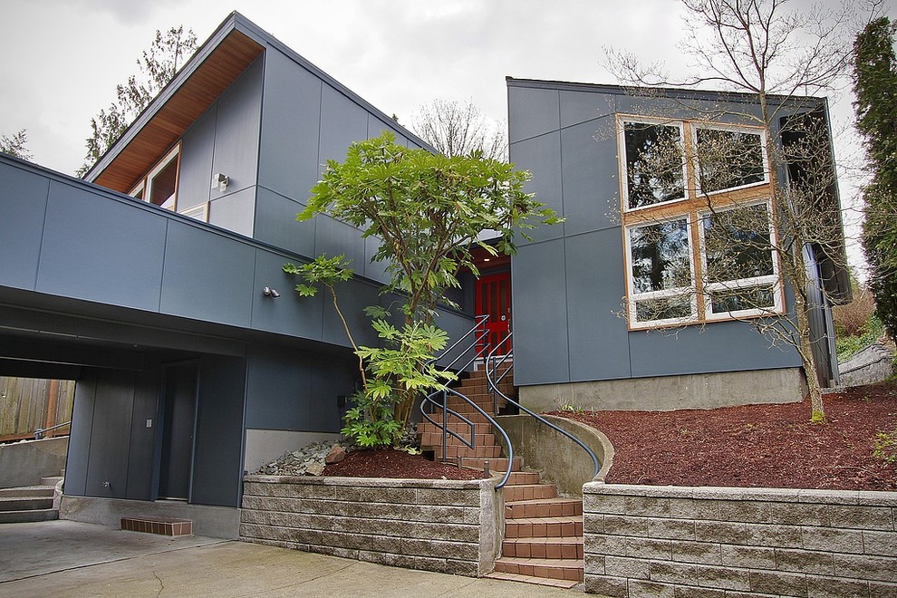 Exemple d'une façade de maison métallique et bleue moderne de taille moyenne et à un étage avec un toit en appentis.