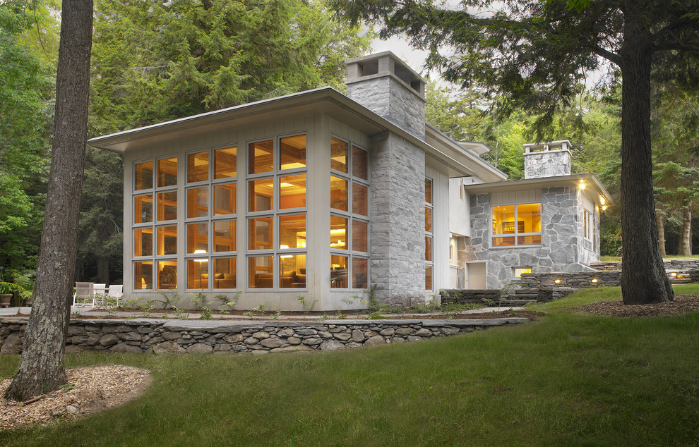 Immagine della facciata di una casa contemporanea a un piano con rivestimento in pietra e terreno in pendenza
