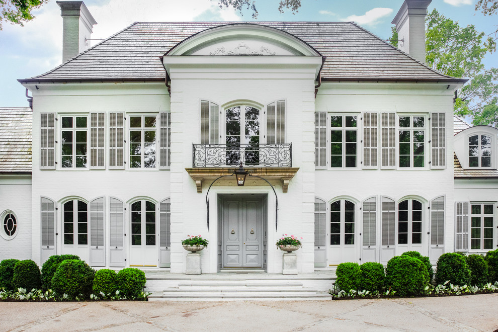 Aménagement d'une grande façade de maison blanche classique à un étage avec un toit à quatre pans et un toit en shingle.