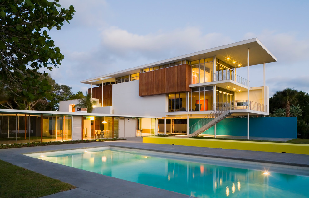 This is an example of a midcentury house exterior in Tampa with three floors, wood cladding and a flat roof.