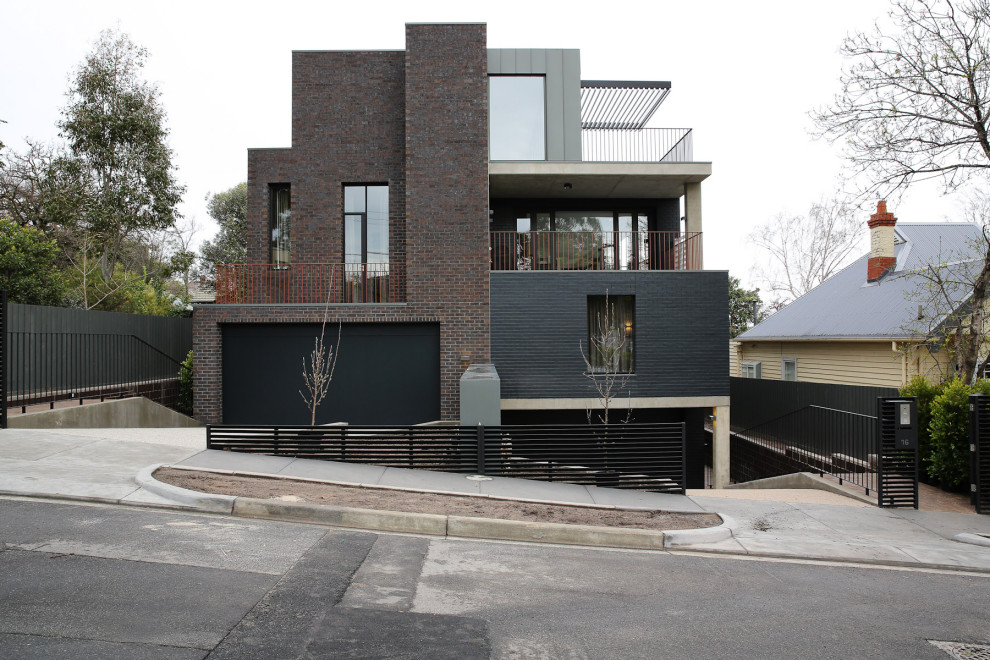 Foto de fachada de casa bifamiliar negra moderna grande de tres plantas con revestimiento de ladrillo, tejado plano y tejado de metal