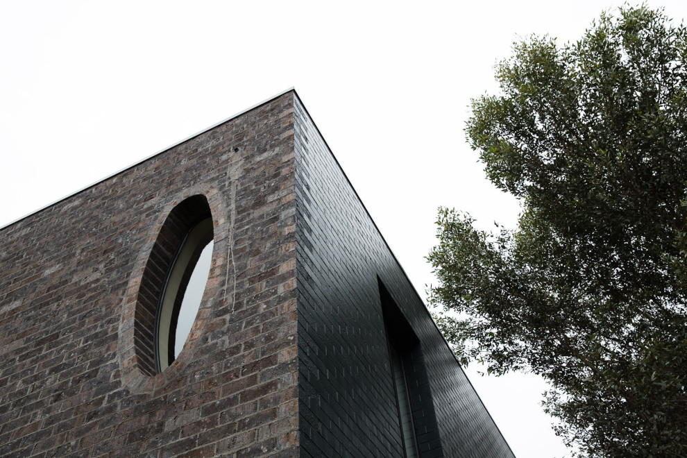 Ejemplo de fachada de casa bifamiliar negra moderna grande de tres plantas con revestimiento de ladrillo, tejado plano y tejado de metal
