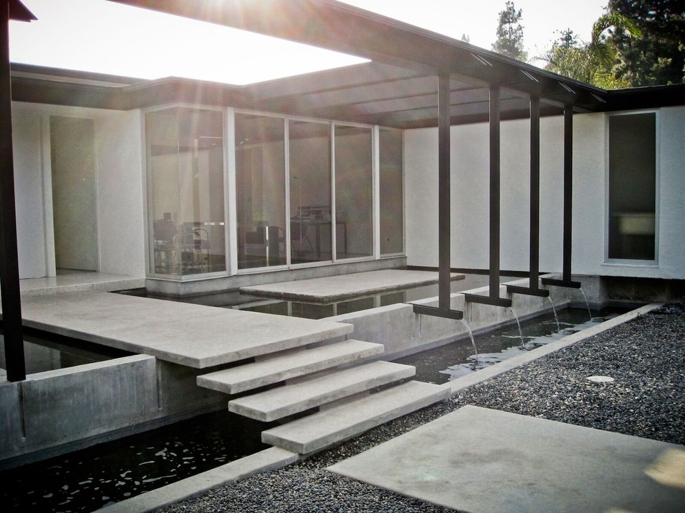 This is an example of a white and medium sized midcentury bungalow render detached house in Los Angeles with a flat roof.