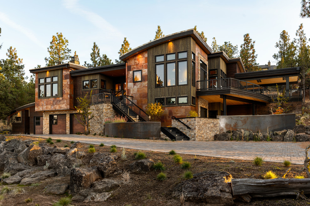 На фото: двухэтажный, коричневый частный загородный дом в стиле рустика с комбинированной облицовкой и плоской крышей с