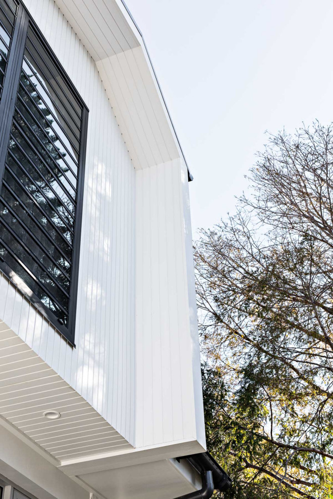 Modelo de fachada de casa blanca contemporánea de tamaño medio de dos plantas con revestimiento de madera, tejado a dos aguas y tejado de metal