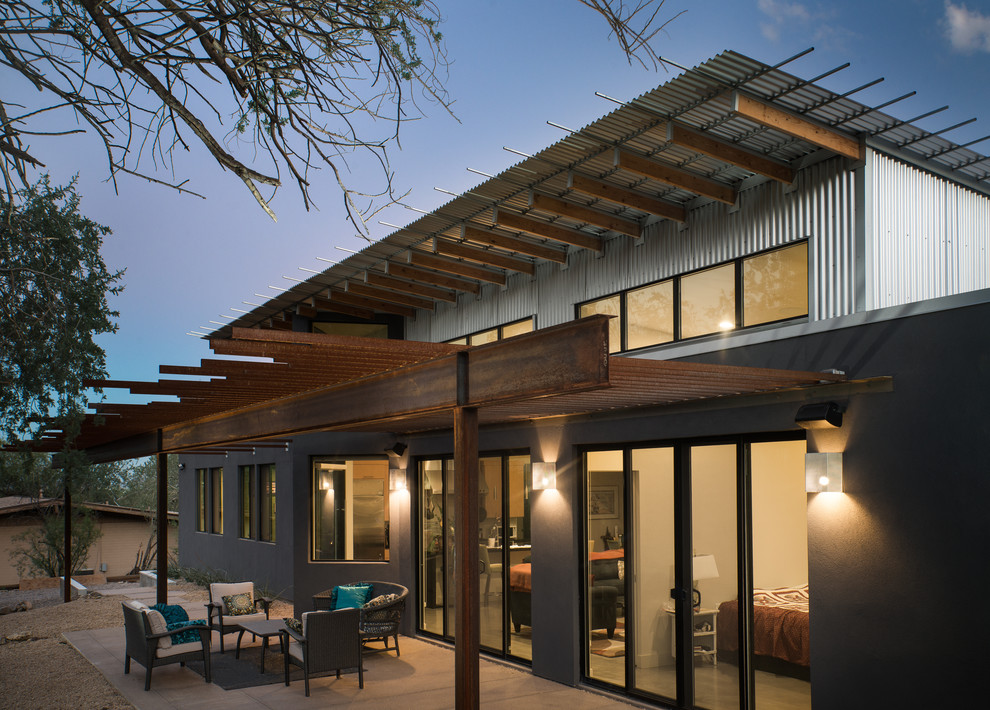Ejemplo de fachada de casa gris moderna de tamaño medio de una planta con revestimiento de metal y tejado de teja de madera