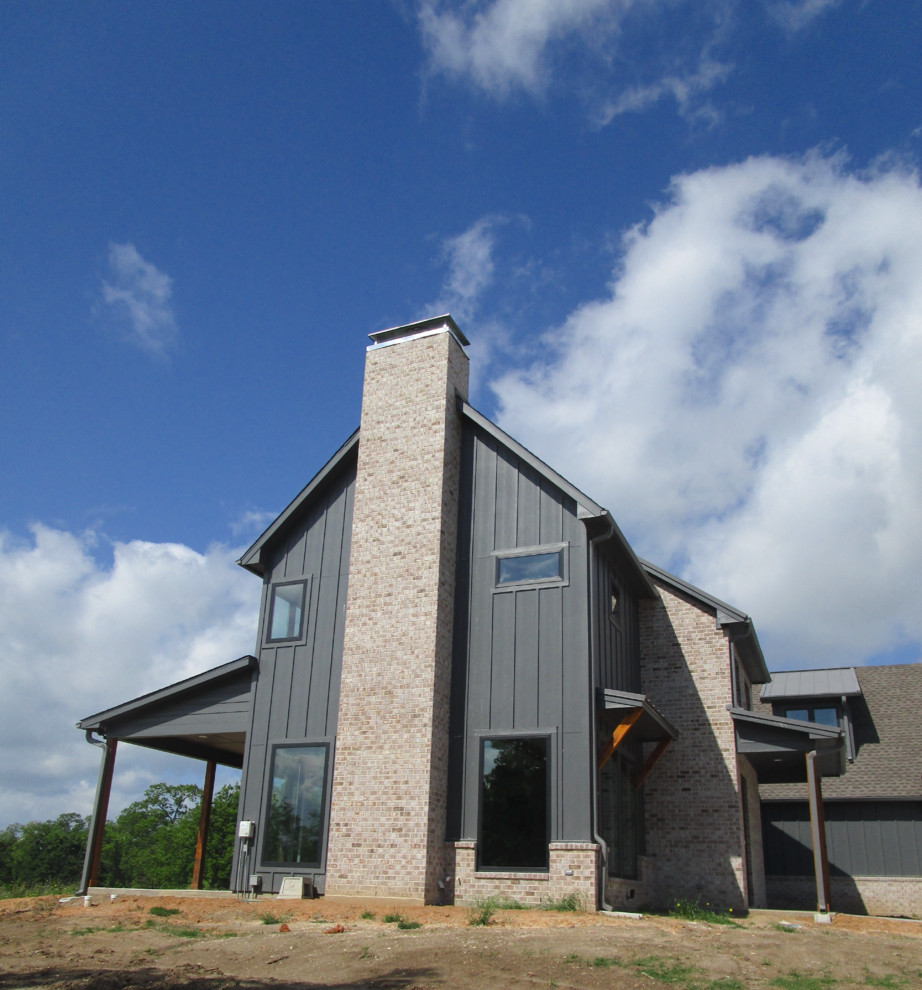 На фото: двухэтажный, деревянный, серый частный загородный дом среднего размера в современном стиле с двускатной крышей и крышей из гибкой черепицы с