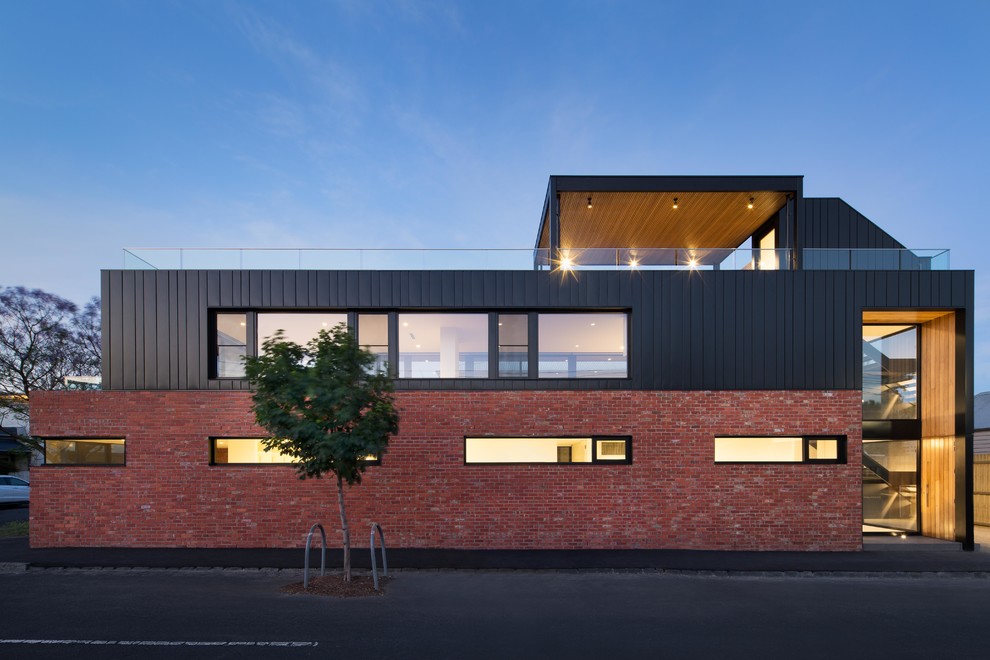 This is an example of a medium sized and black modern two floor brick detached house in Melbourne.