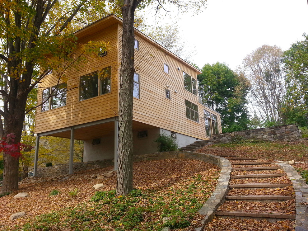 Imagen de fachada de casa beige moderna pequeña de dos plantas con revestimiento de madera, tejado plano y tejado de teja de madera