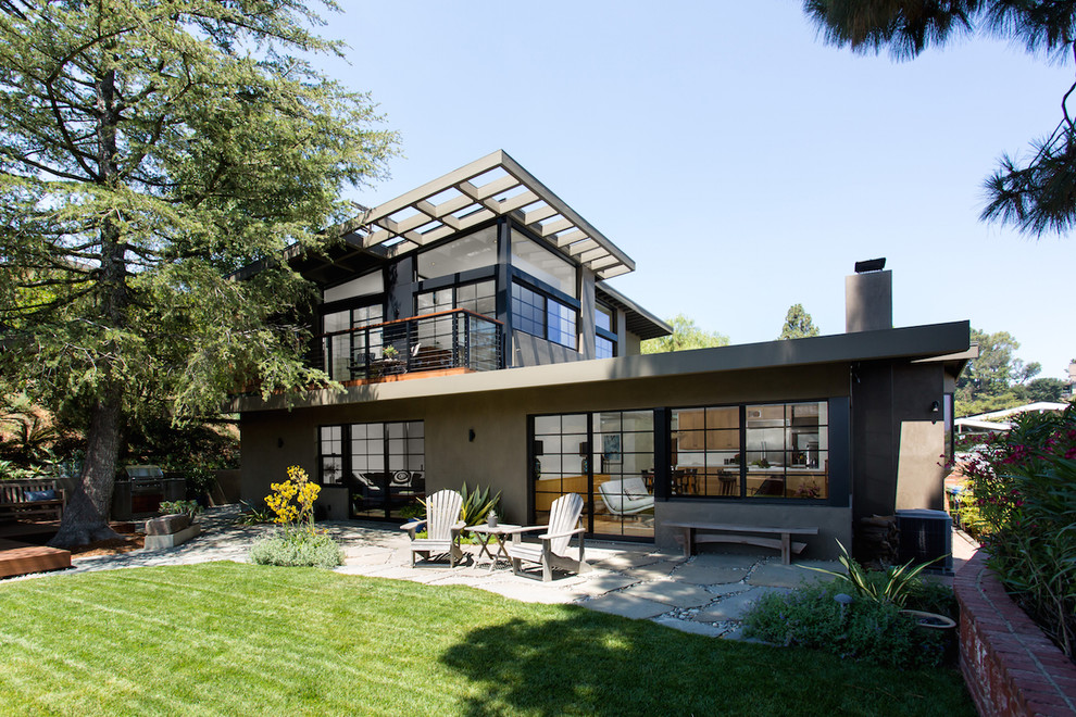 Inspiration for a large mid-century modern green two-story stucco house exterior remodel in Los Angeles with a shed roof and a metal roof