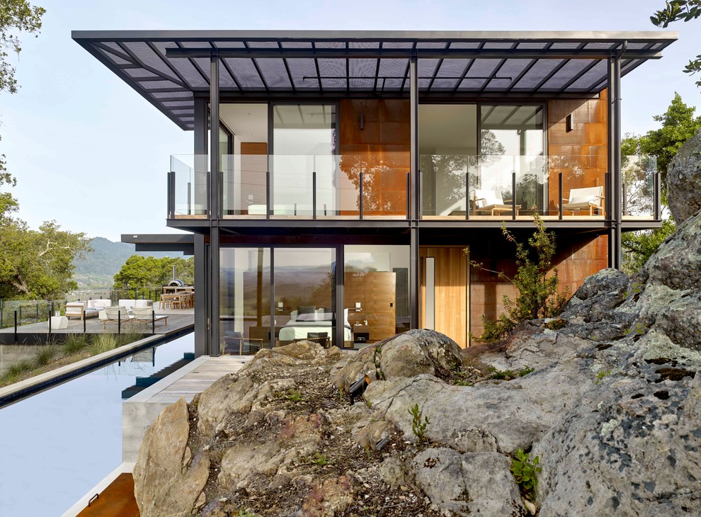 Пример оригинального дизайна: двухэтажный, коричневый частный загородный дом в современном стиле с облицовкой из металла и плоской крышей