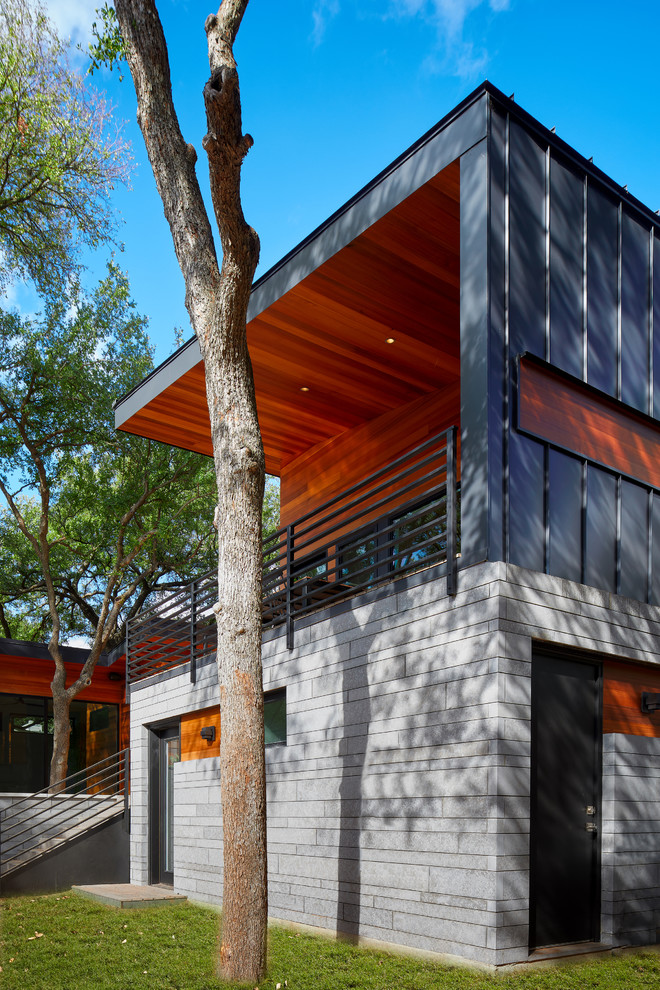Imagen de fachada de casa retro a niveles con revestimientos combinados y tejado de metal
