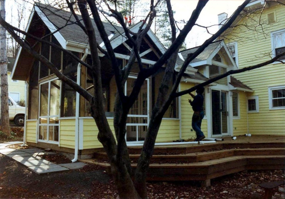 Foto della facciata di una casa piccola gialla classica a un piano con rivestimento in legno