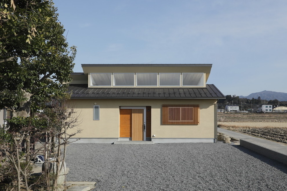 Immagine della facciata di una casa piccola beige etnica a un piano con rivestimento in stucco e copertura in metallo o lamiera