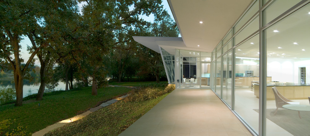 Aménagement d'une grande façade de maison blanche moderne en verre de plain-pied avec un toit plat.