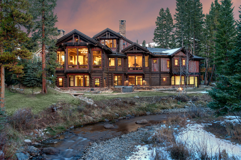 This is an example of a rustic house exterior in Denver with three floors, wood cladding and a pitched roof.