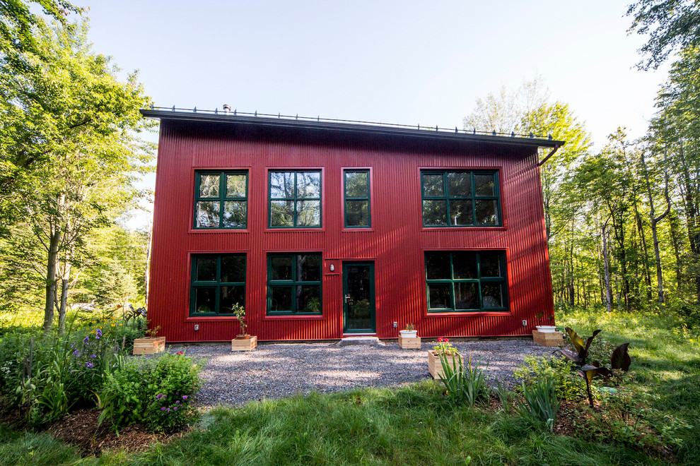 На фото: большой, двухэтажный, деревянный, красный частный загородный дом в стиле рустика с двускатной крышей и металлической крышей с