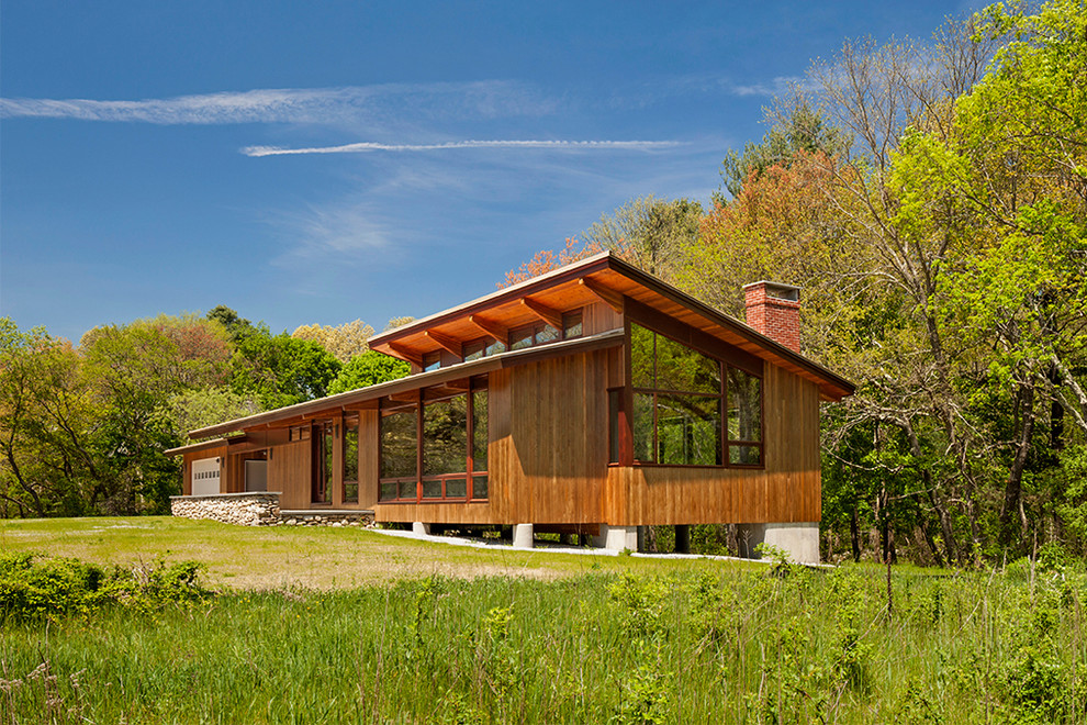 На фото: одноэтажный, деревянный, коричневый частный загородный дом в стиле рустика с односкатной крышей
