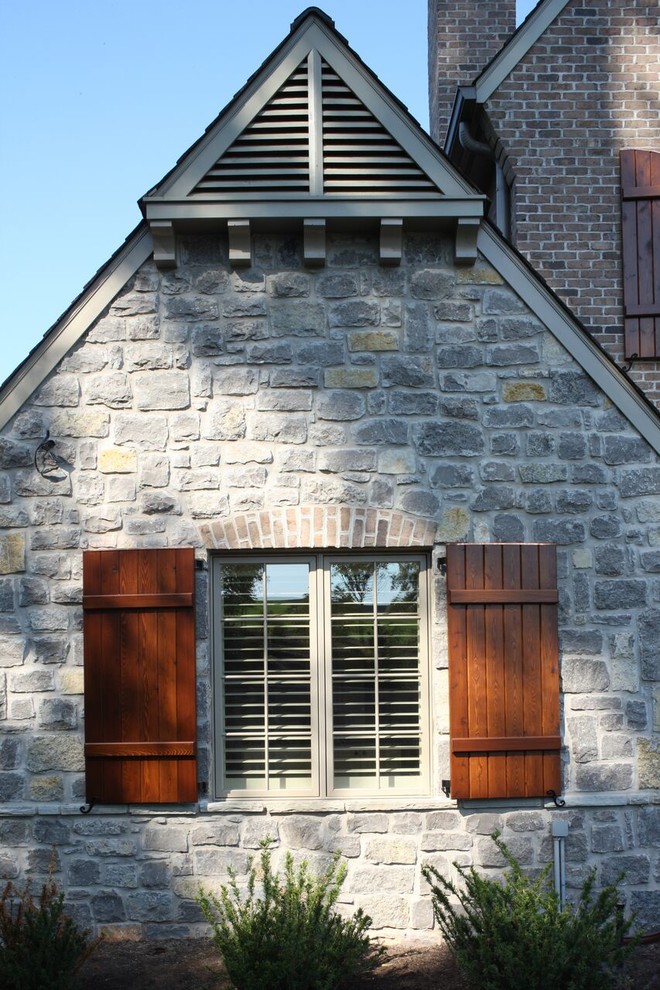 Immagine della facciata di una casa grande grigia american style a due piani con rivestimento in pietra e tetto a capanna
