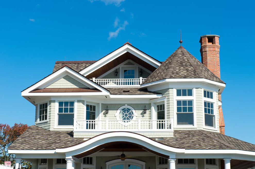 Cette image montre une grande façade de maison verte marine en bois à deux étages et plus avec un toit à deux pans.