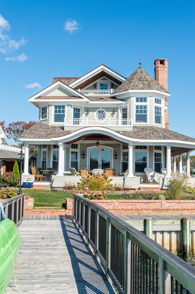 На фото: трехэтажный, большой, деревянный, зеленый дом в викторианском стиле с двускатной крышей