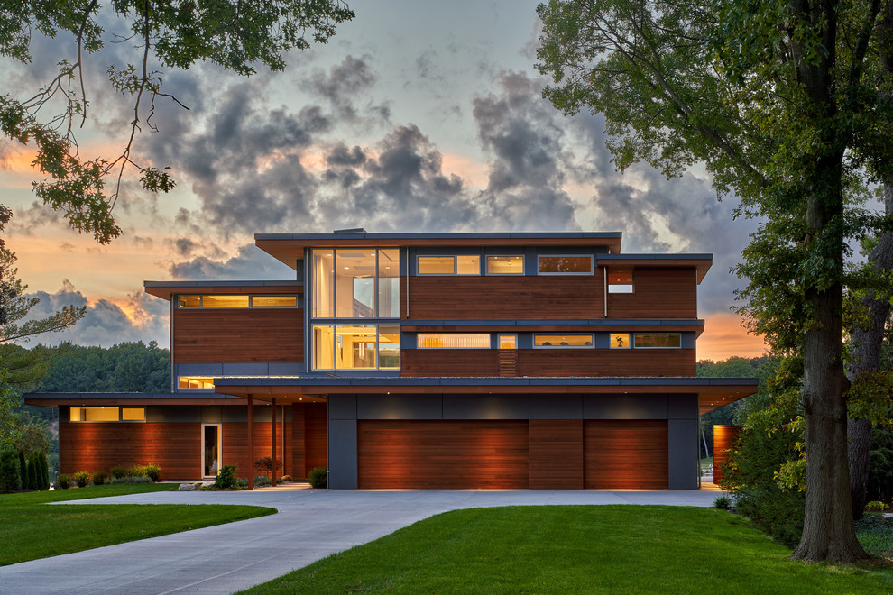 This is an example of a brown contemporary detached house in Grand Rapids with three floors, wood cladding and a flat roof.